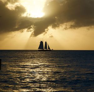 Silhouette sailboat sailing on sea against sky during sunset