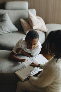 High angle view of siblings reading comics at home