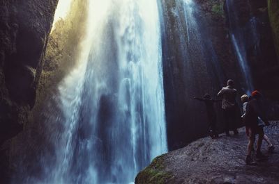 Man with children standing by waterfall