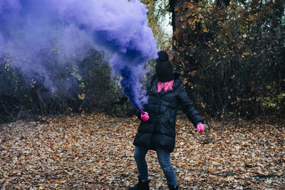 Woman wearing mask while holding distress flare in forest