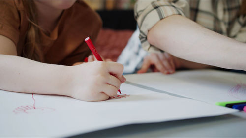 Midsection of teacher teaching drawing to kid