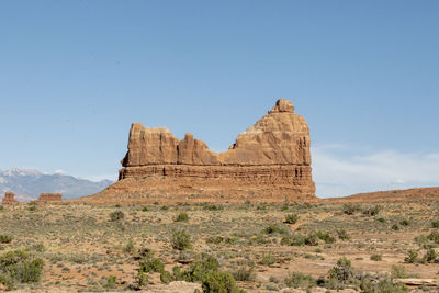 Rock formations on landscape against clear blue sky