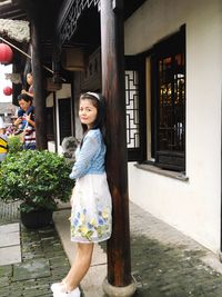 Portrait of happy woman standing in front of footpath