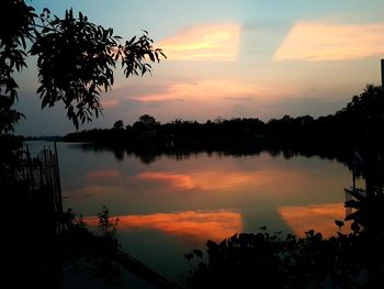 Silhouette trees by lake against sky during sunset