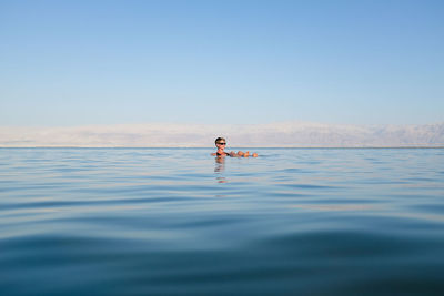 Person in sea against clear sky
