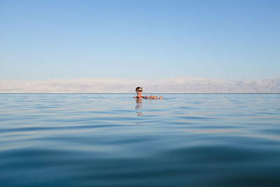 Woman relaxing in sea against sky