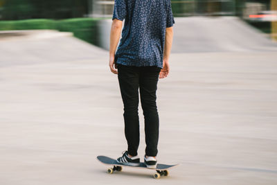 Low section of man standing on skateboard in city