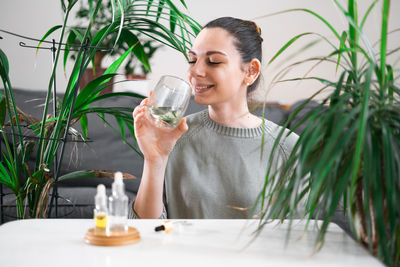 Portrait of young woman drinking water while sitting at home