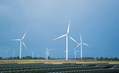 Windmill on field against clear blue sky