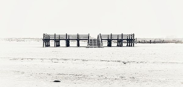 Wooden posts on beach against clear sky