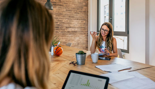 Woman using phone while sitting on table