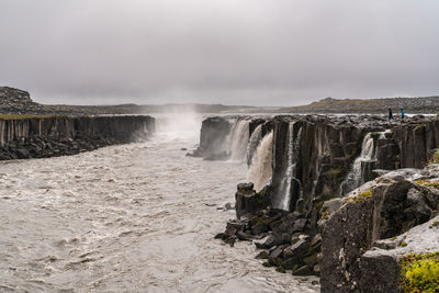 Scenic view of waterfall against sky