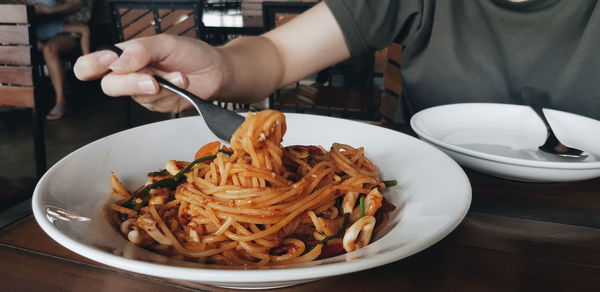 Close-up of person preparing food in plate on table