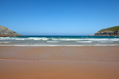 A quiet fine sandy beach with cliffs in the background