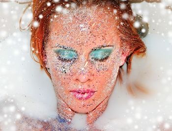 Close-up of young woman with glitter on face taking milkbath