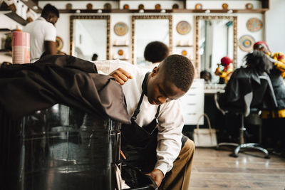 Young male barber opening drawer in hair salon