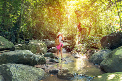 Woman standing by rocks in forest