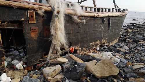 View of abandoned boat moored at sea shore