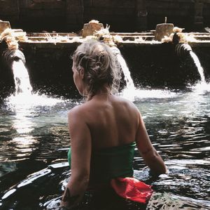 Rear view of shirtless man standing in lake