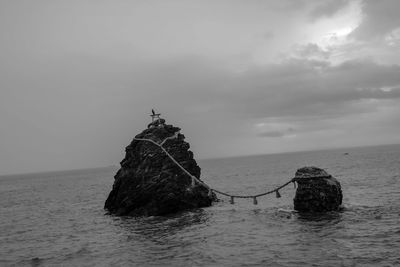 Scenic view of rock in sea against sky