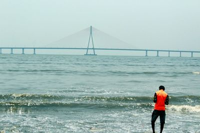 Rear view of man standing by suspension bridge