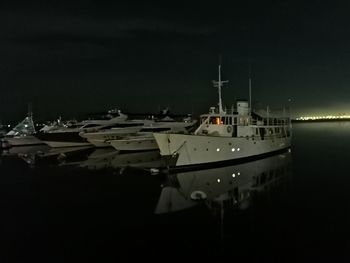 Boats moored in harbor at night