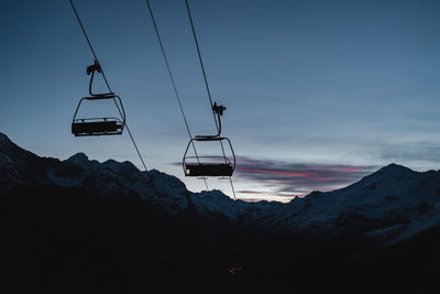 Ski lift over snowcapped mountains against sky during sunrise