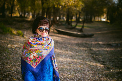 Portrait of smiling young woman against trees