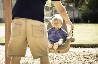 Father pushing child on swing