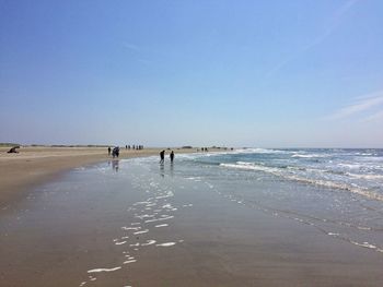 People at beach against blue sky