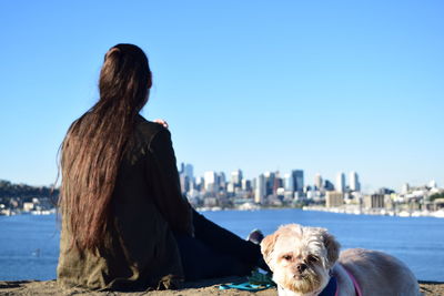 Woman looking at city buildings against clear blue sky