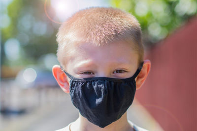 Close-up portrait of boy wearing mask standing outdoors