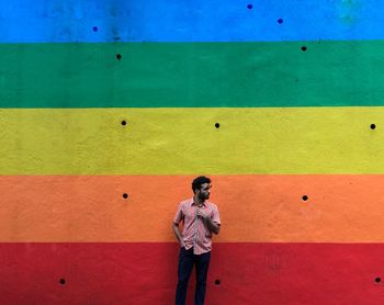 Man looking away while standing against multi colored wall