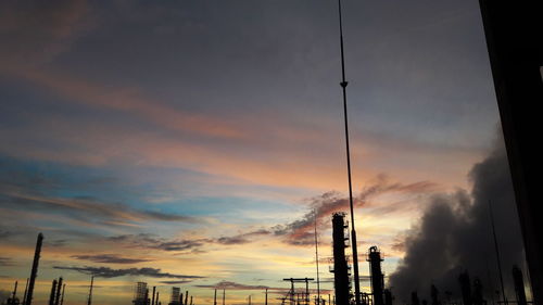 Low angle view of silhouette cranes against sky during sunset