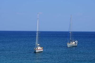 Sailboat on sea against clear blue sky