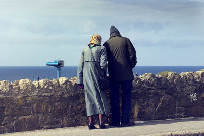 Rear view of people standing by sea against sky