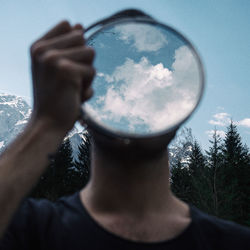 Close-up of man covering face with mirror