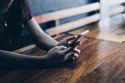 Midsection of man using mobile phone on table