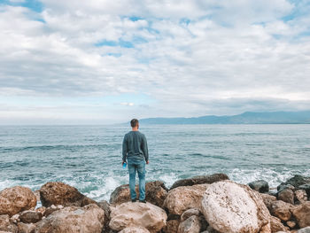 Rear view of man looking at sea against sky