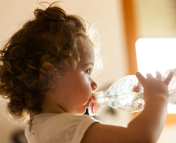 Close-up of cute girl drinking water at home