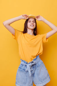 Portrait of smiling teenager girl against yellow background