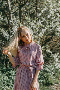 Blonde girl on a spring walk in the garden with cherry blossoms. female portrait, close-up. 