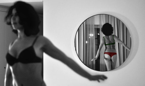 Rear view of woman standing in mirror