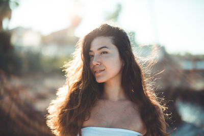 Portrait of smiling young woman standing against sky