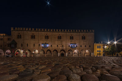 Crowd on street against illuminated buildings in city at night