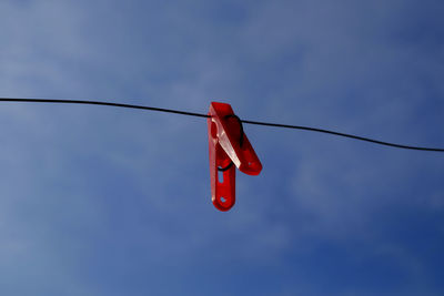Low angle view of clothespin hanging on clothesline against blue sky