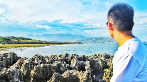 Rear view of man standing in sea against sky