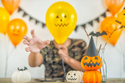 Midsection of man holding pumpkin against orange during halloween