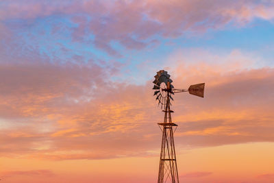 Low angle view of traditional windmill against sky during sunset