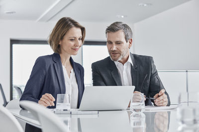 Businessman and businesswoman having a meeting in office with laptop